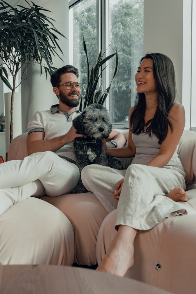 woman in black tank top sitting on couch beside man in white pants