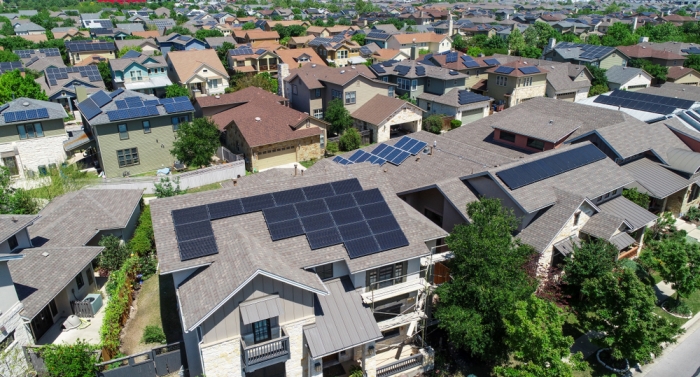 Aerial view of a neighborhood featuring several homes with solar panels on their roofs.