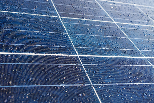 A close-up view of raindrops sitting on the smooth surface of a solar panel.
