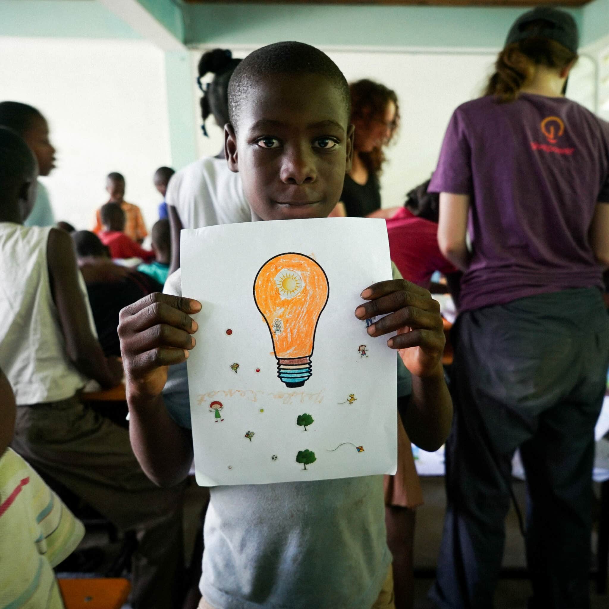 Child holding drawing of lightbulb colored orange