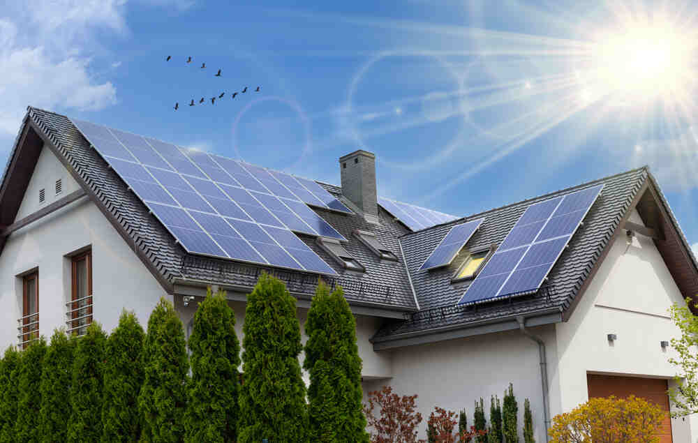 Solar panels on a large home roof with rays of sun.
