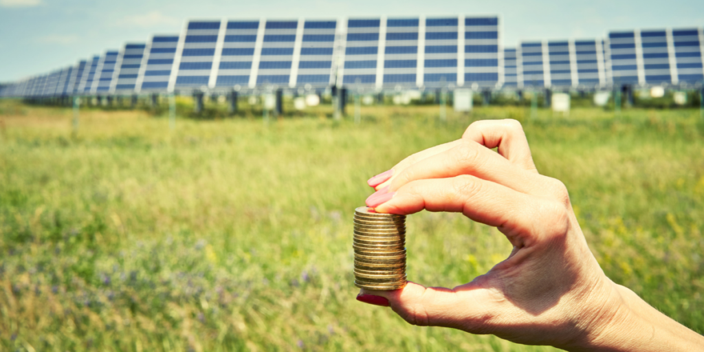 Solar panels and a hand holding a stack of coins.