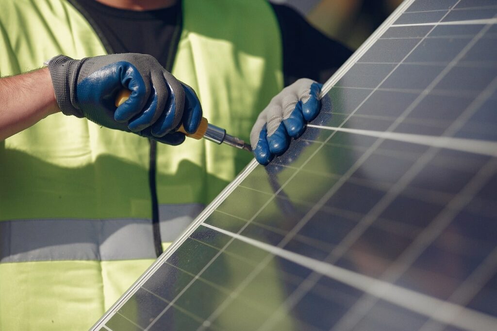 A worker installs solar panels on a roof.